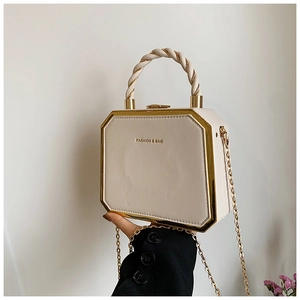 Close-up of beige octagonal box bag with gold metal trim and woven rope handle
