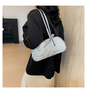 Detail of silver bow shoulder bag with wavy texture on a model's arm in city style