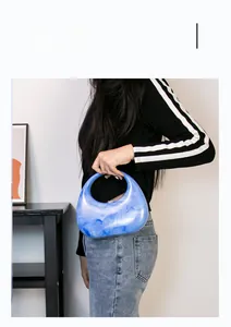 Detail of blue marble acrylic crescent handbag with artistic swirl pattern and top handle