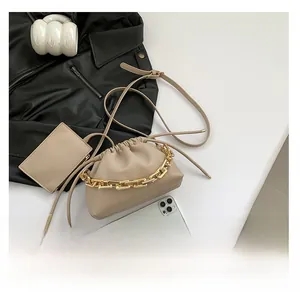 Detail of beige pleated cloud bag with gold chunky chain handle and mini accessory pouch