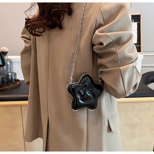 Detail of black star shaped crossbody bag with smiling face pattern and silver chain