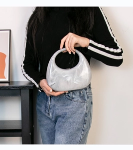 Close-up of marble pattern acrylic handbag with unique circular handle and moon shape design