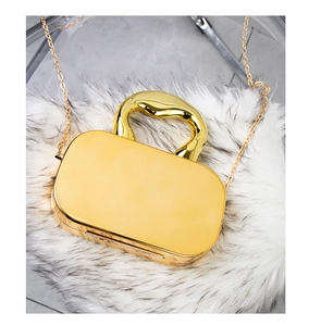 Detail of mirror gold clutch with unique wave handle and metal chain on white fur