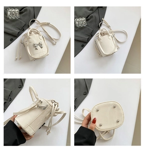 Detail view of cream mini bucket bag with metallic bow and polished leather texture