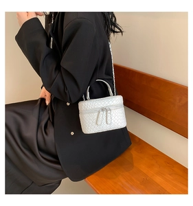 Dettaglio di una mini borsa a secchiello bianca intrecciata con catena argento e manico corto
