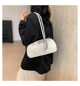 Detail view of cream shoulder bag with wave texture and checkered bow on a model