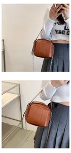 Detailaufnahme der braunen gewebten Eimertasche mit Lederstreifen und silberner Kette