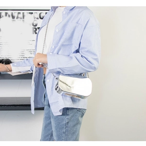 Detail view of a silver mirror finish mini crossbody bag with a metal chain strap