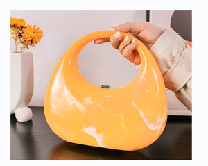 Close-up of bright orange marble texture acrylic crescent bag with metal clasp