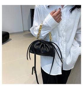 Detail of black pleated bucket bag featuring lychee grain leather and gold chain handle
