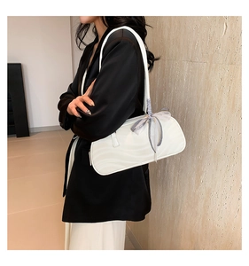 Detail of white bow shoulder bag featuring wave stitching and checkered ribbon accents