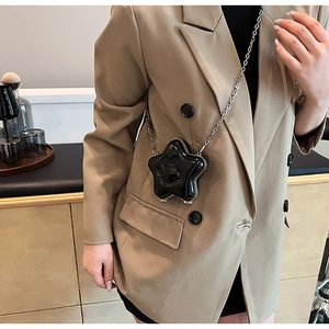 Detail of star-shaped crossbody bag with glossy finish and smiling face pattern