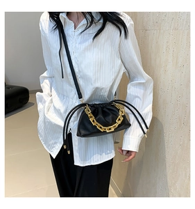 Detail of black lychee leather bucket bag with thick gold chain handle and drawstring