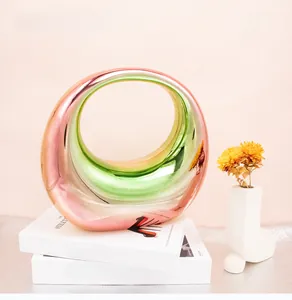 Irregular circular gradient acrylic moon bag on books with floral accents and soft lighting