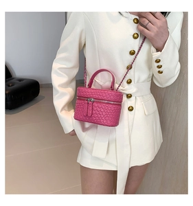 Dettaglio della mini borsa a secchiello rosa intrecciata con catena in metallo e doppia zip