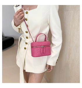Mini borsa a secchiello rosa intrecciata con doppia zip e catena indossata da modella