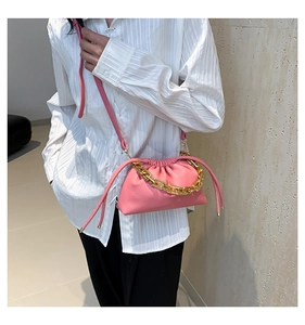 Close-up of pink ruched cloud bag with chunky gold chain and leather shoulder strap