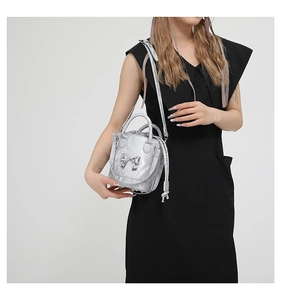 Detail of silver metallic bucket bag with 3D bow and textured finish on a model