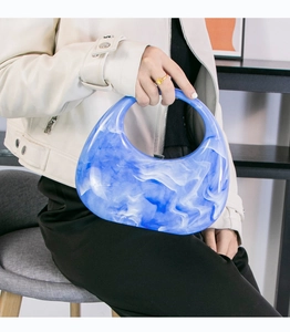 Detailed texture of blue and white marble acrylic crescent handbag held by model
