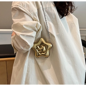 Detail view of gold star shaped mini crossbody bag with heart relief and metal chain strap