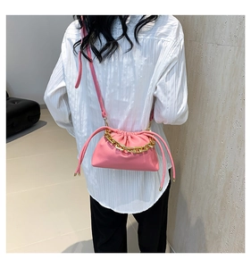 Detail of pink pleated cloud bag featuring decorative gold chain and slim shoulder strap