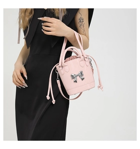 Detailed view of pink bucket bag with silver metal bow and drawstring closure
