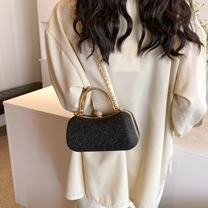 Elegant black glitter evening clutch with gold metal handle and pearl clasp detail