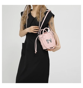 Detail of pink bucket bag with silver metal bow accent and drawstring closure