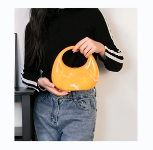 Close-up of bright orange marble acrylic handbag with unique crescent hollow handle