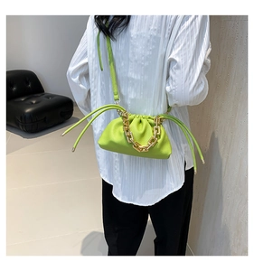 Detail view of neon green pouch bag with thick gold chain strap and drawstring design