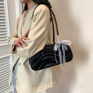 Fashionable black wavy texture handbag with lace bow detail shown on a model
