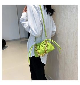 Detail of green ruched cloud bag with bold gold chain accessory and shoulder strap