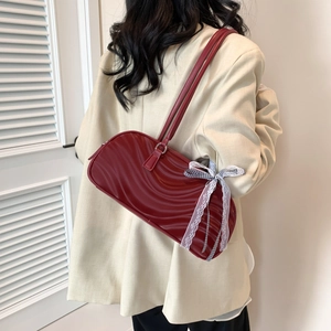Deep red wavy texture shoulder bag with plaid bow detail worn by a model