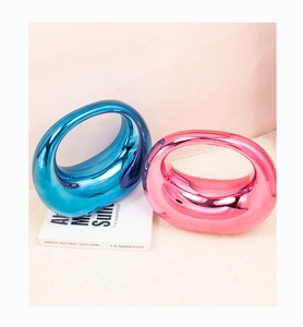 Detail of blue and pink metallic crescent handbags with glossy mirror finish on white book