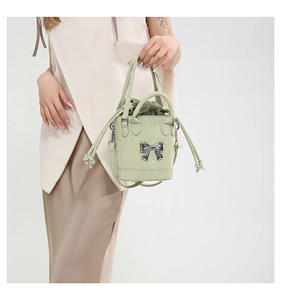 Detailed view of light green bucket bag with a bow knot and drawstring inner pouch