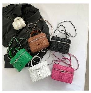 Dettaglio di mini borse a tracolla intrecciate in cinque colori con catenella