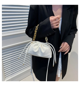 Close-up of white ruched bucket bag with chunky gold chain handle and shoulder strap