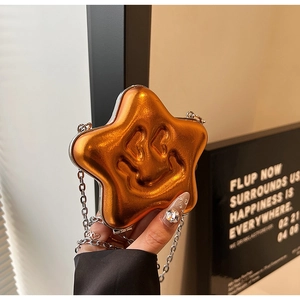 Close-up of a star-shaped orange metallic mini bag with a smiley face and silver chain