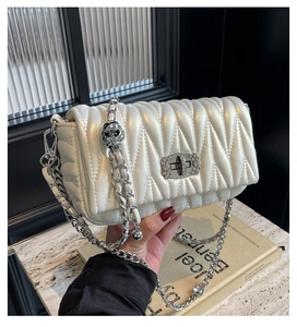 Detail of white quilted leather handbag with silver chain and crystal metal lock clasp