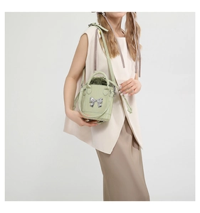 Detail of light green bucket bag with a silver metal bow and drawstring inner lining