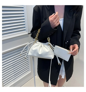 Close-up of a white pleated dumpling bag with chunky gold chain and mini pouch accessory