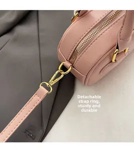 Detail view of pink leather handbag showing detachable golden hook and sturdy stitching