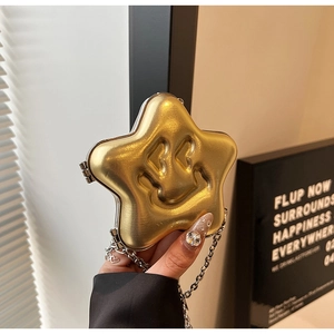 Macro detail of a golden star-shaped handbag with a heart-eyed smiley face and chain