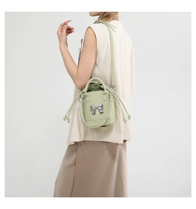 Detail of light green bucket bag showing silver metal bow and drawstring inner bag
