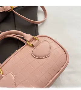 Detail of pink croc-embossed leather handbag showing stitching and gold hardware