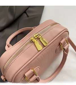 Detail of pink crocodile embossed handbag with gold double zippers and hardware