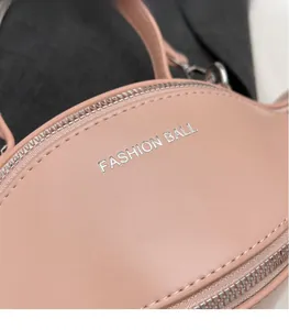 Détail du sac en cuir rose clair avec logo Fashion Ball argenté et fermeture éclair en métal
