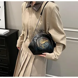 Detail of vintage black shell bag with elephant embroidery and metal clasp on a model