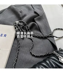 Detail of black quilted leather crossbody bag with elegant silver chain shoulder strap
