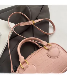 Detailed shot of pink crocodile pattern bag showing heart-shaped handle base and gold hardware